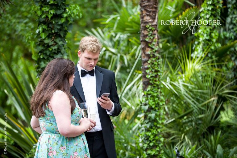 Wedding guests checking their iPhone during drinks reception at Hampton Court House Surrey