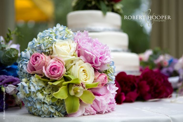 Bride's bouquet on table with wedding cake at reception at Hampton Court House Surrey
