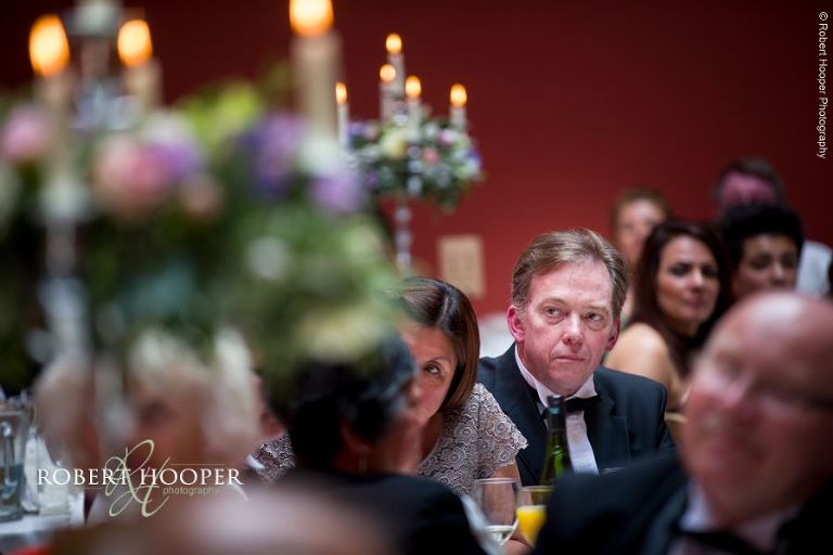 Wedding guests listening tentatively to speeches during wedding breakfast at Hampton Court House Surrey