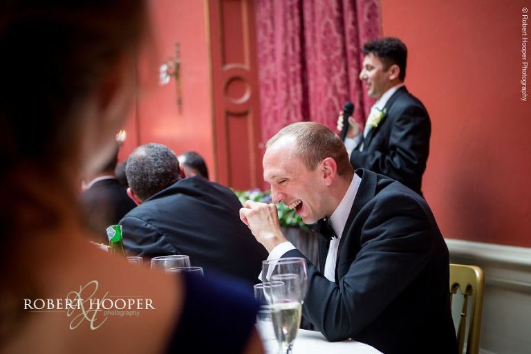 Wedding guest laughing at funny groom speech at wedding breakfast held at Hampton Court House Surrey