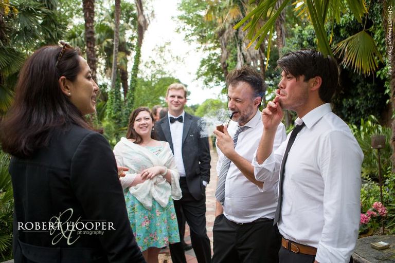 Wedding guests smoking outside in gardens before evening reception on wedding day at Hampton Court House Surrey