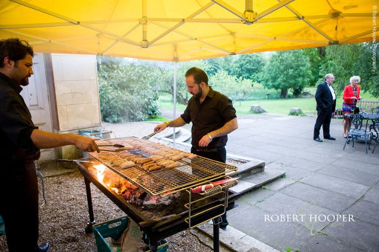 Sausages on the barbeque for evening reception on wedding day at Hampton Court House Surrey