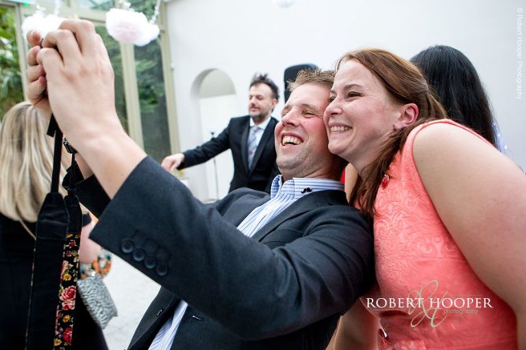 Wedding guests taking a selfie on dance floor during evening reception at Hampton Court House Surrey