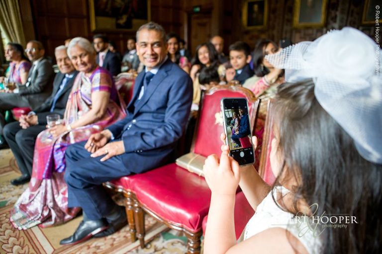 Young girl taking photos on her Dad's iPhone at Hindu wedding ceremony at Middle Temple