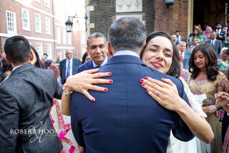 Bride hugs wedding guests goodbye before leaving with her groom in horse and cart at Middle Temple London