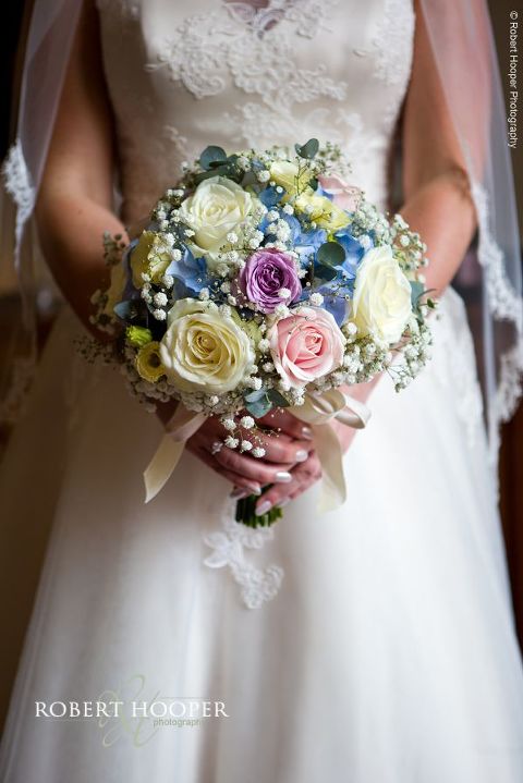 Bride holding bouquet of roses and gyp on wedding day at Wotton House Dorking Surrey