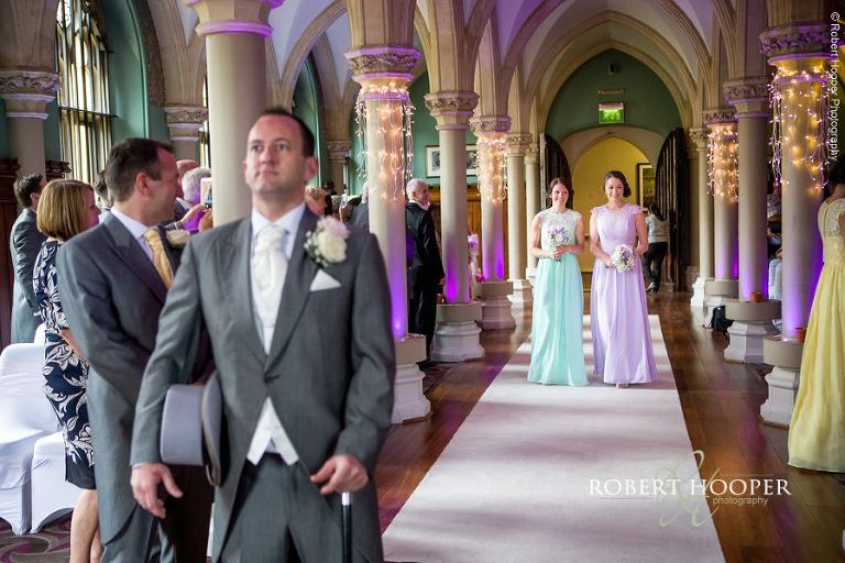 Groom looking nervous as bridesmaids walk down the isle on wedding day at Wotton House Surrey