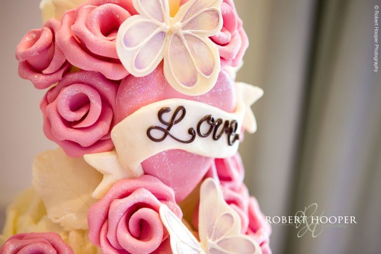 Choccywoccydoodah pink and white rose and butterfly wedding cake with love written on front in milk chocolate for wedding day at Wotton House Dorking Surrey