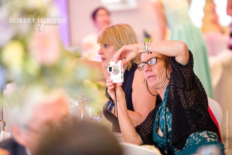 Wedding guest taking photo during speeches at wedding breakfast at Wotton House Dorking Surrey