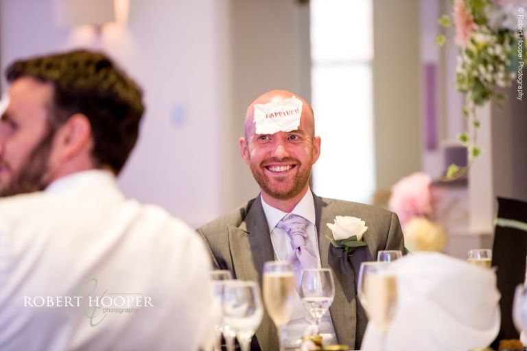 Wedding guest with sticker on forehead as part of game during wedding breakfast speeches at Wotton House Dorking Surrey
