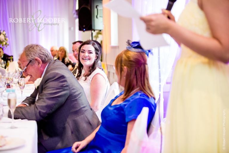 Bride laughing at bridesmaid speech during wedding breakfast at Wotton House Surrey