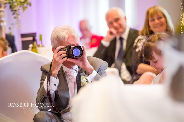Wedding guest taking photos during speeches at wedding breakfast at Wotton House Dorking Surrey