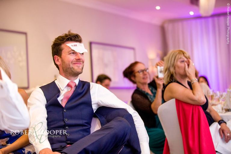 Wedding guest with sticker on forehead as part of game during wedding breakfast speeches at Wotton House Dorking Surrey