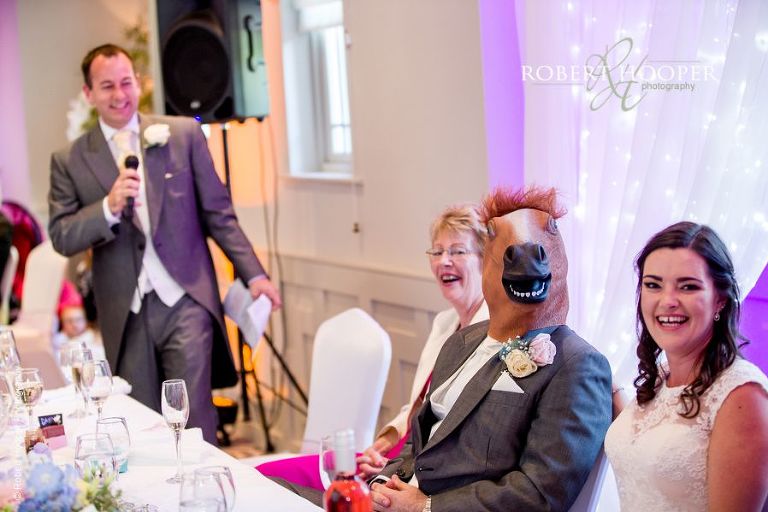 Groom wearing horse's head as part of best man's speech on wedding day at Wotton House Dorking Surrey
