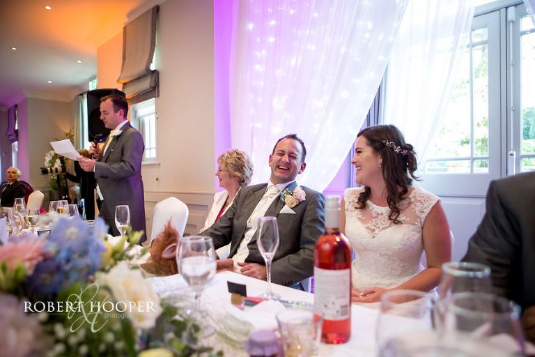 Groom laughing at twin brother's / best man's speech during wedding breakfast at Wotton House Dorking Surrey