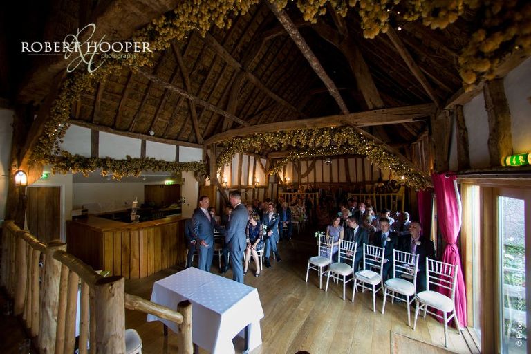 Groom and guests seated for wedding ceremony in the barn at The Crown Inn Pishill Oxfordshire
