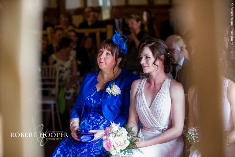 Mother of the bride and bridesmaid seated during civil wedding ceremony in the barn at The Crown Inn Pishill Oxfordshire