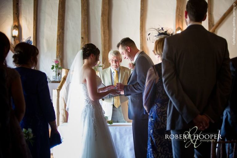 Bride and groom exchange rings during civil wedding ceremony in the barn at The Crown Inn Pishill Oxfordshire