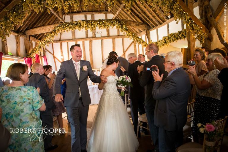 Bride and groom come back down the isle as man and wife after their civil wedding ceremony in the barn at The Crown Inn Pishill Oxfordshire