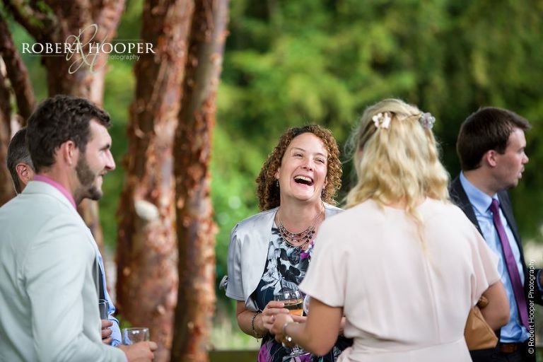 Wedding guests on the back lawn whilst room is turned around for evening party on wedding day at The Crown Inn Pishill Oxfordshire