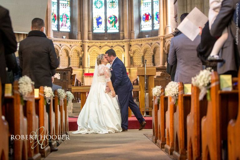 Bride and groom kissing during wedding ceremony at St Matthew's Church, Surbiton Surrey