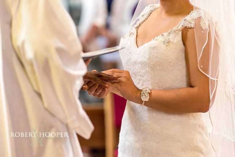 Bride placing wedding ring on groom's finger during wedding ceremony at St John the Divine Church South Croydon Surrey