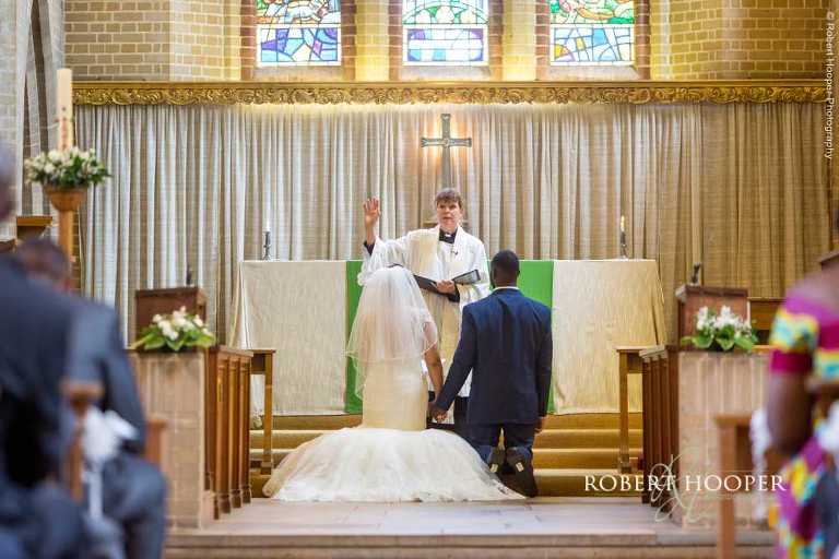 Vicar blessing the bride and groom during marriage service at St John the Divine South Croydon Surrey