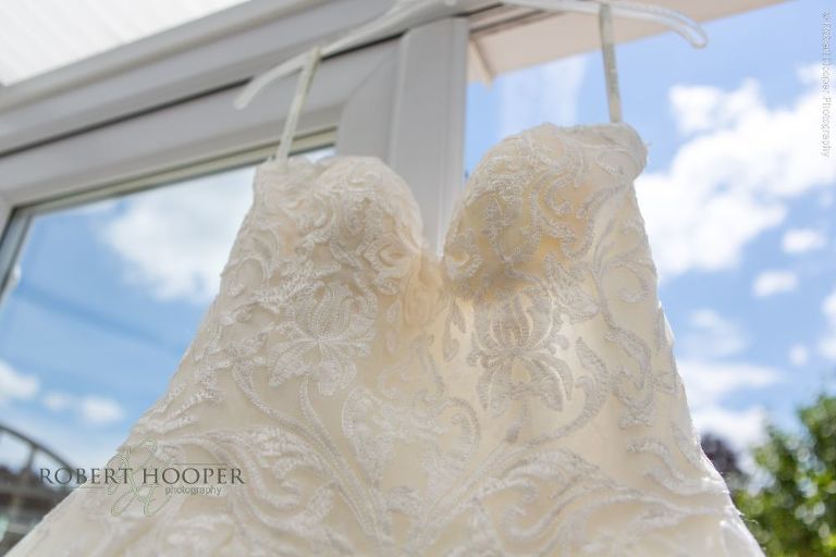 White wedding dress hanging in conservatory