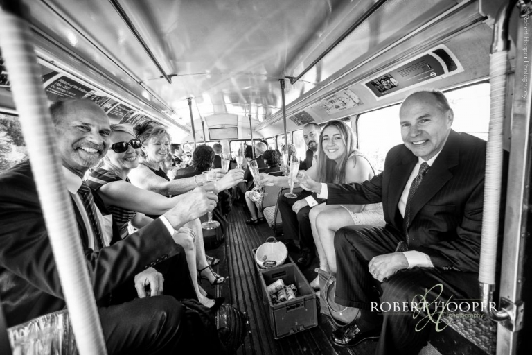 Guests boarding red London bus on wedding day Addington Palace